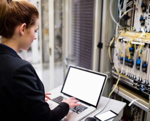 Technician using laptop while analyzing server